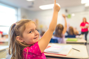 Elementary female student raising hand in class.